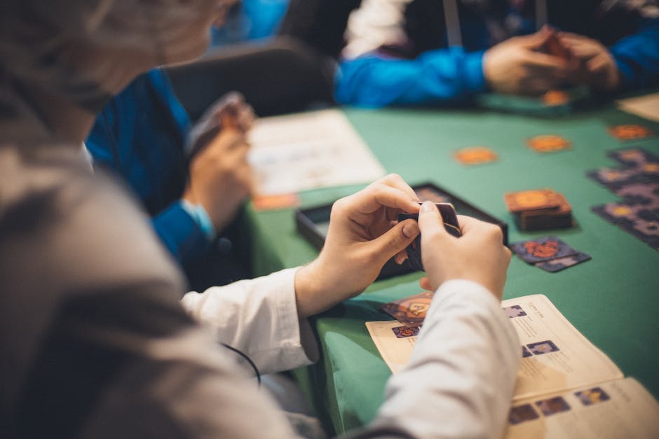 A group of people gathered around a table playing a card game with concentration.