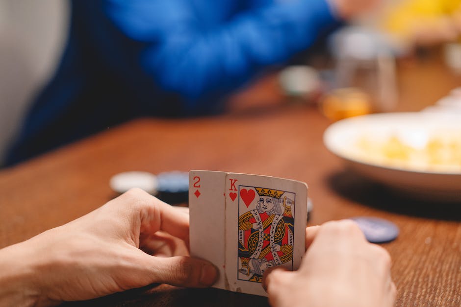 Two pairs of hands holding cards facing down on a table, ready to start a game of Euchre.