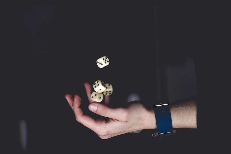 A person playing Yahtzee and holding five dices in their hand with a focused expression.