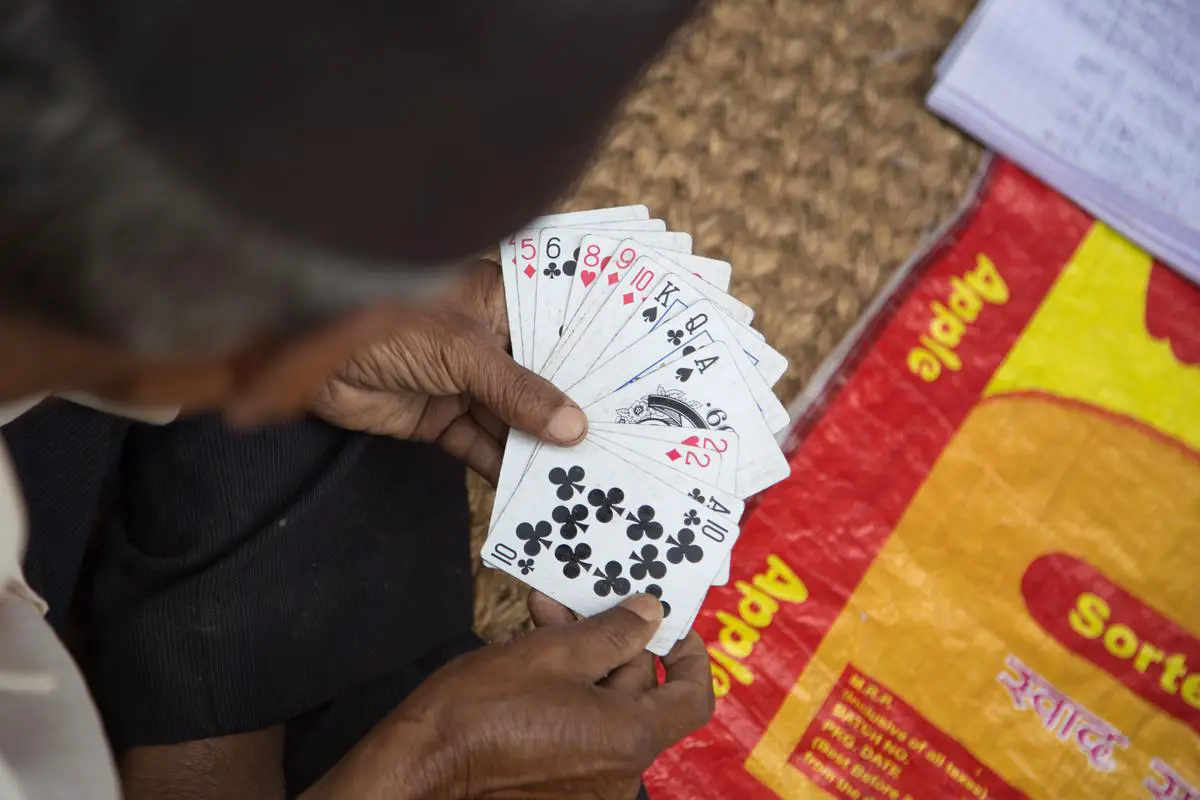 An image of three players sitting around a table, playing Spite and Malice with cards spread out in front of them.