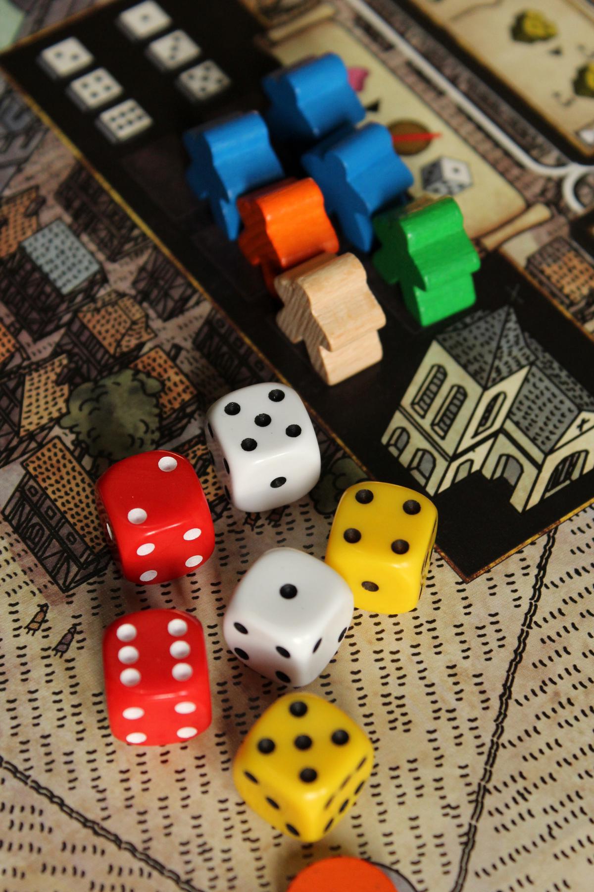 A group of people playing Trivial Pursuit around a table, with a game board, question cards, and wedges visible