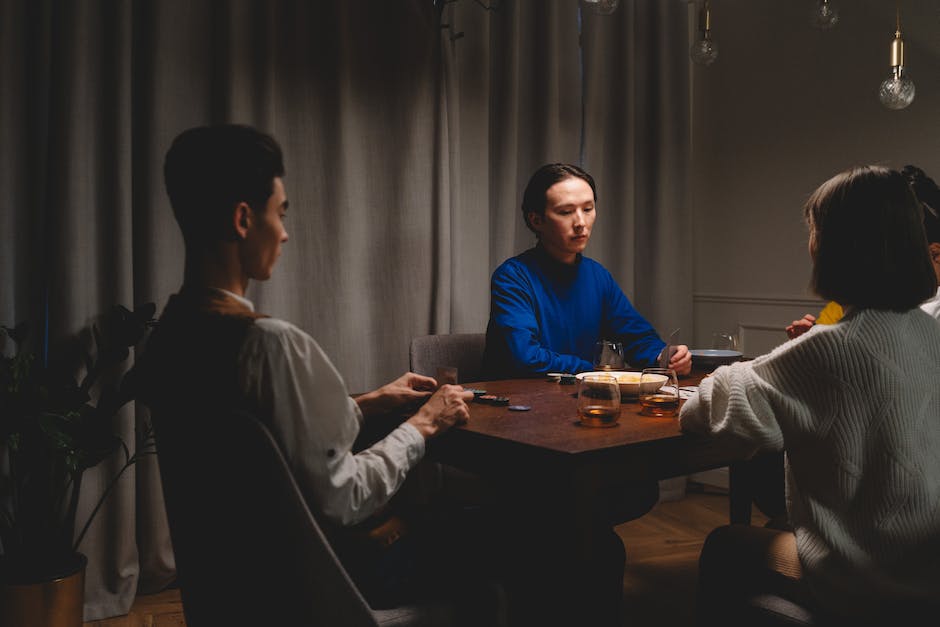 A group of people playing a Bicycle card game, seated around a table, engaged in the game and enjoying each other's company.