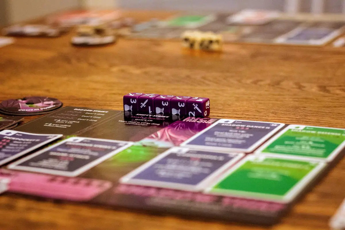 A group of people sitting around a table, playing the board game Cashflow with a game board and money stacks on the table in front of them.