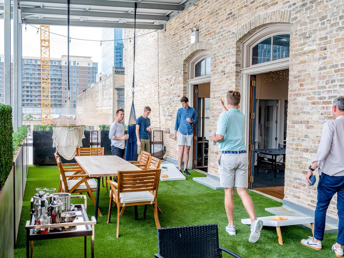 A group of friends playing cornhole in a backyard.