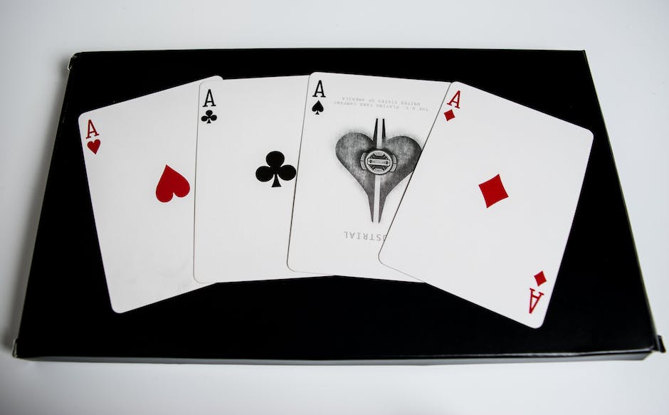 A photo of a cribbage board with pegs and cards on it, with a hand holding some cards in the background.