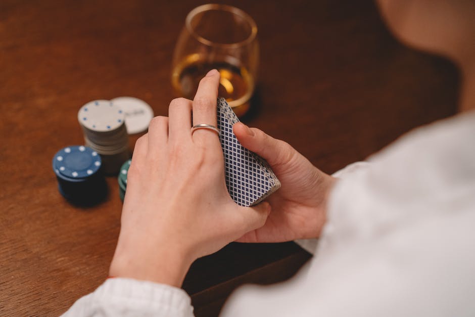 The image shows a hand holding several playing cards, some of which are face-up and some of which are face-down, representing the traditional gameplay style of Pinochle card game.