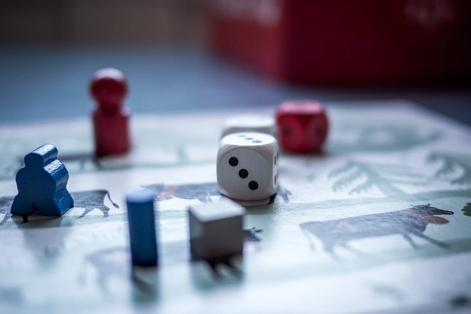 Two guys holding board games, smiling and laughing with coffee cups in front of them.